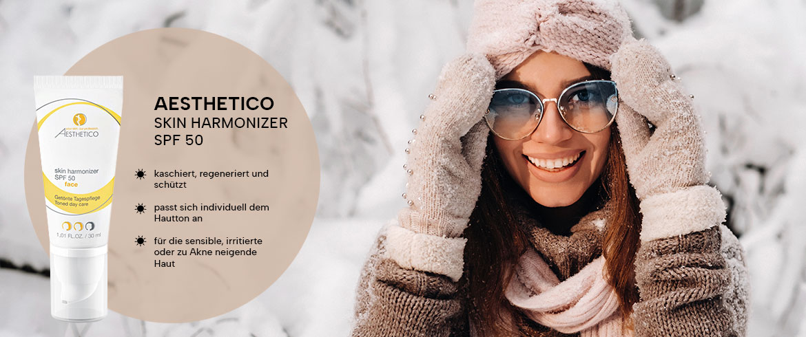 Eine Frau im Schnee trägt Sonnenbrille und bewirbt Aesthetico Skin Harmonizer SPF 50, der sensibler Haut im Winter optimalen UV-Schutz bietet.